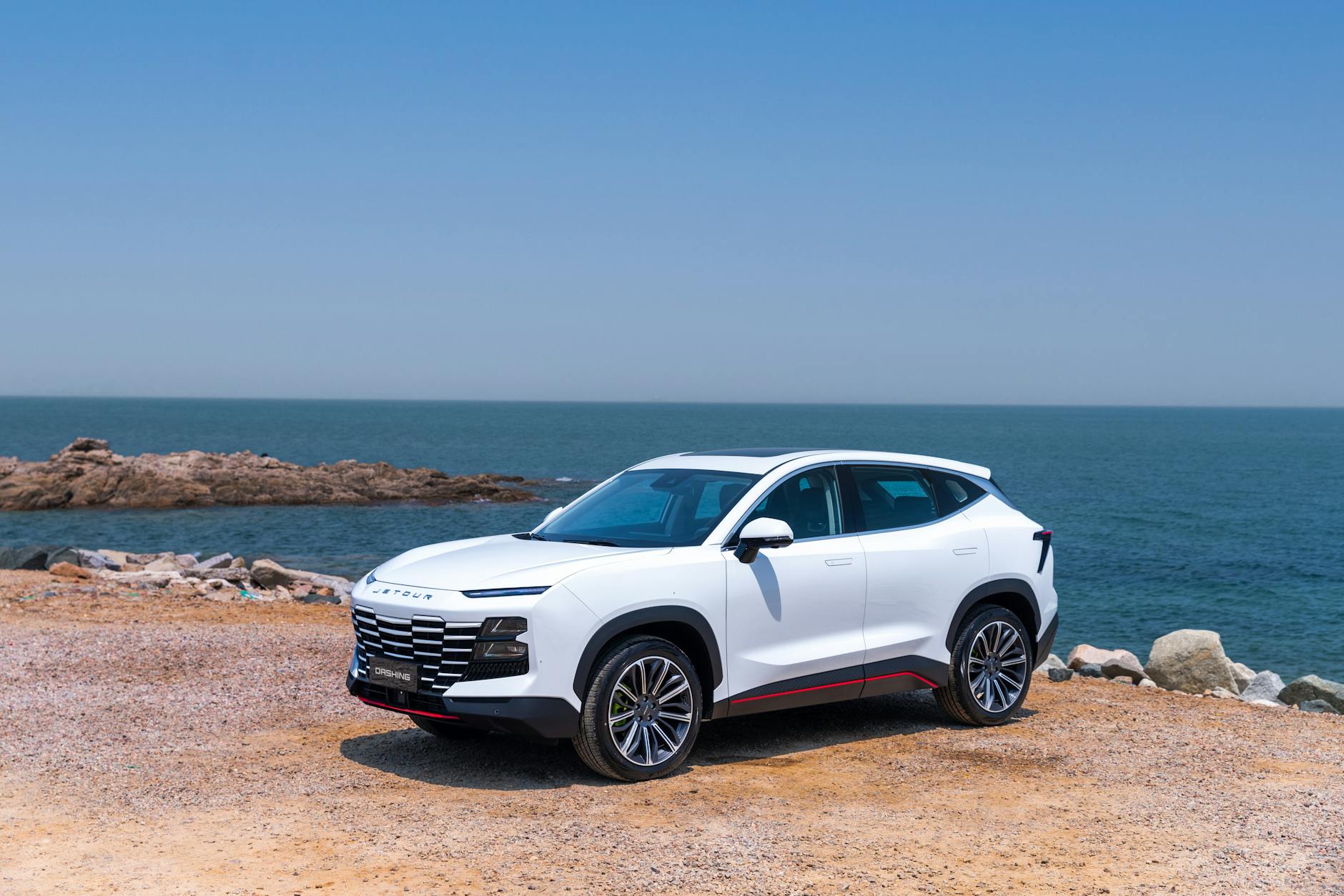 Czy Aston Martin DBX to praktyczny rodzinny SUV analiza kosztów, serwisu i spalania Biały SUV Aston Martin DBX zaparkowany nad morzem w słoneczny dzień