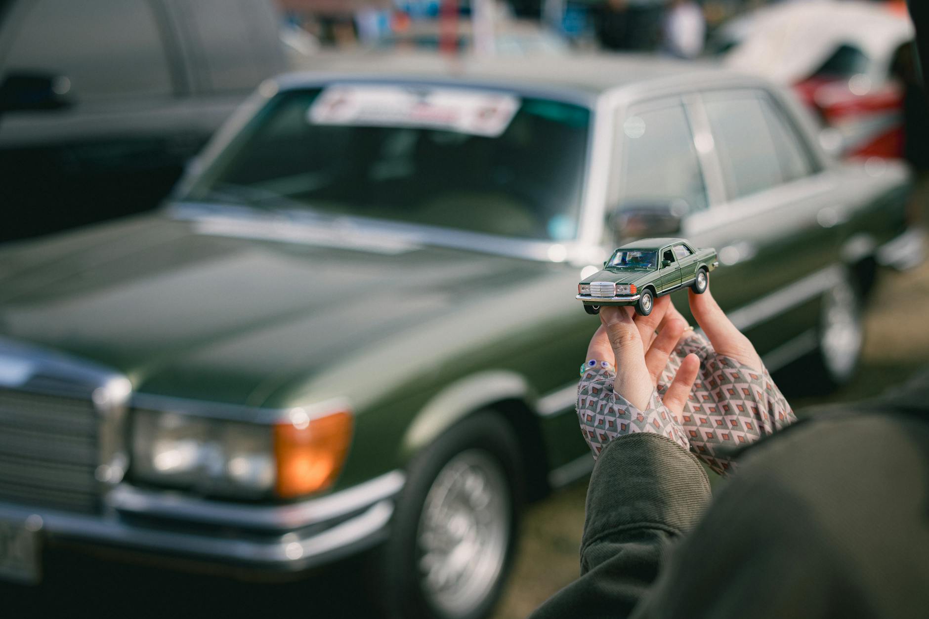Zielony Mercedes W116 i trzymany w dłoniach dopasowany model auta