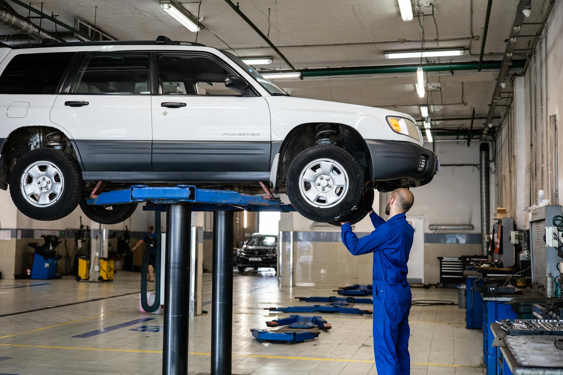 Mechanik ogląda białego Nissana Qashqai na podnośniku w warsztacie