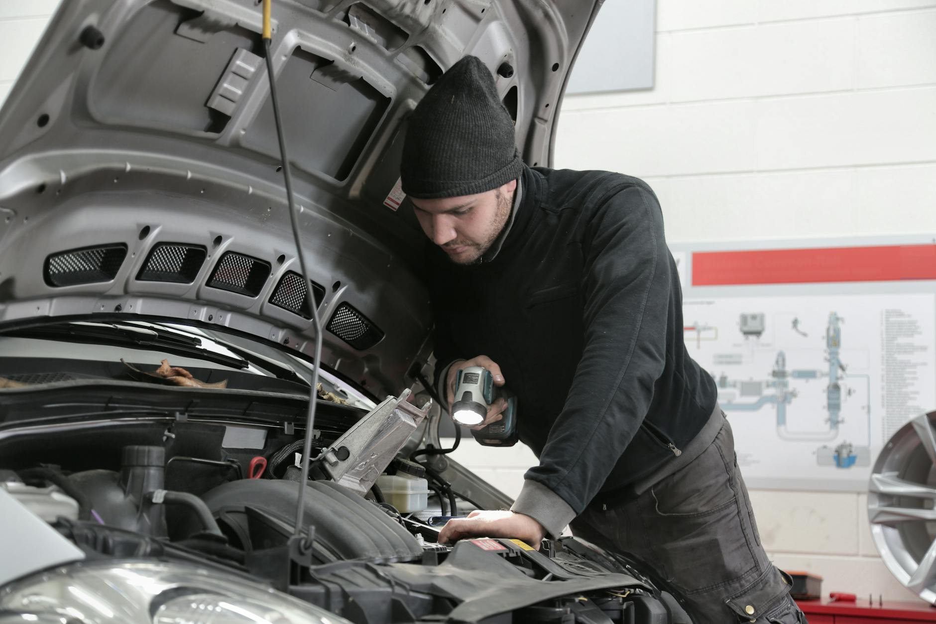 Mechanik z latarką dokładnie ogląda silnik Nissana Qashqai w warsztacie