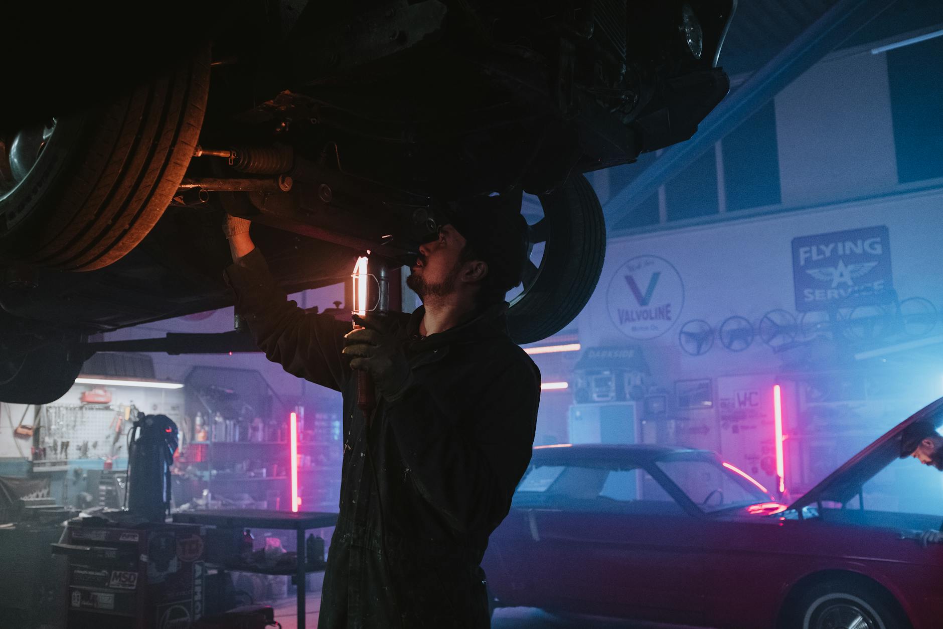 Mechanik sprawdza spód Chevroleta w jasno oświetlonym warsztacie