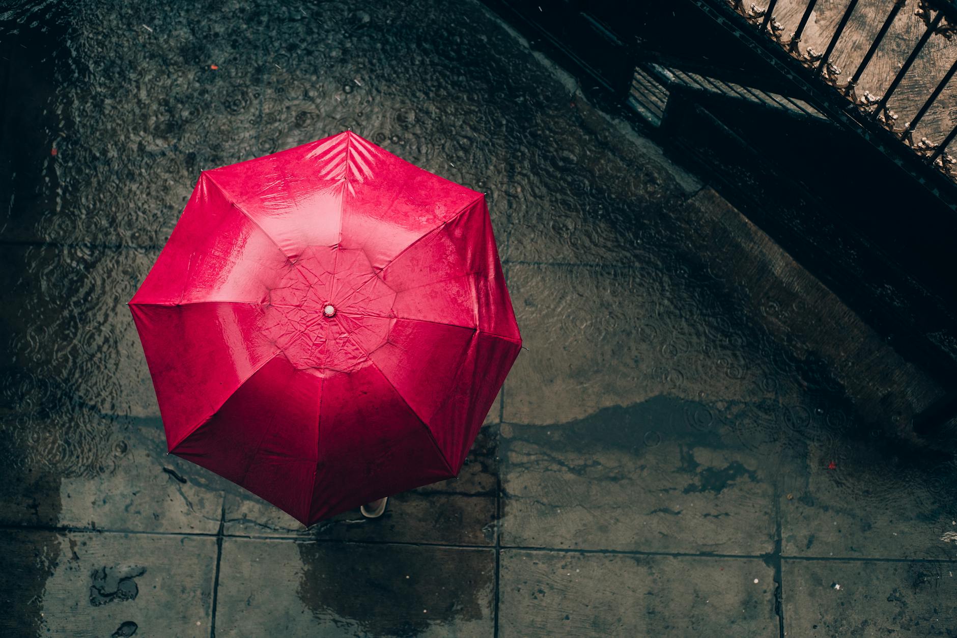Czerwony parasol z lotu ptaka na deszczowej ulicy w mieście