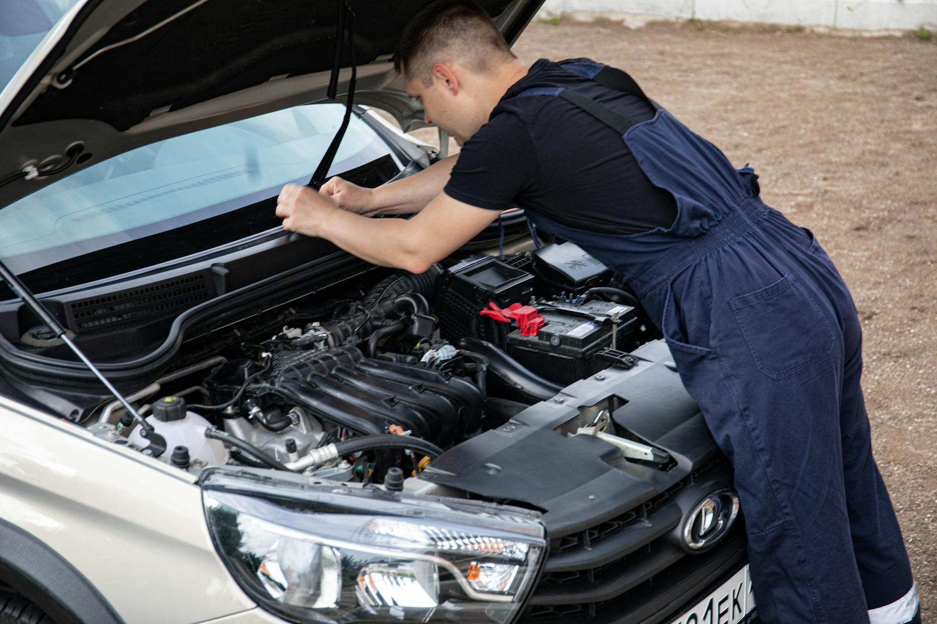 Mechanik pracujący przy silniku Forda EcoBoost pod otwartą maską Mechanik pracujący przy silniku Forda EcoBoost pod otwartą maską