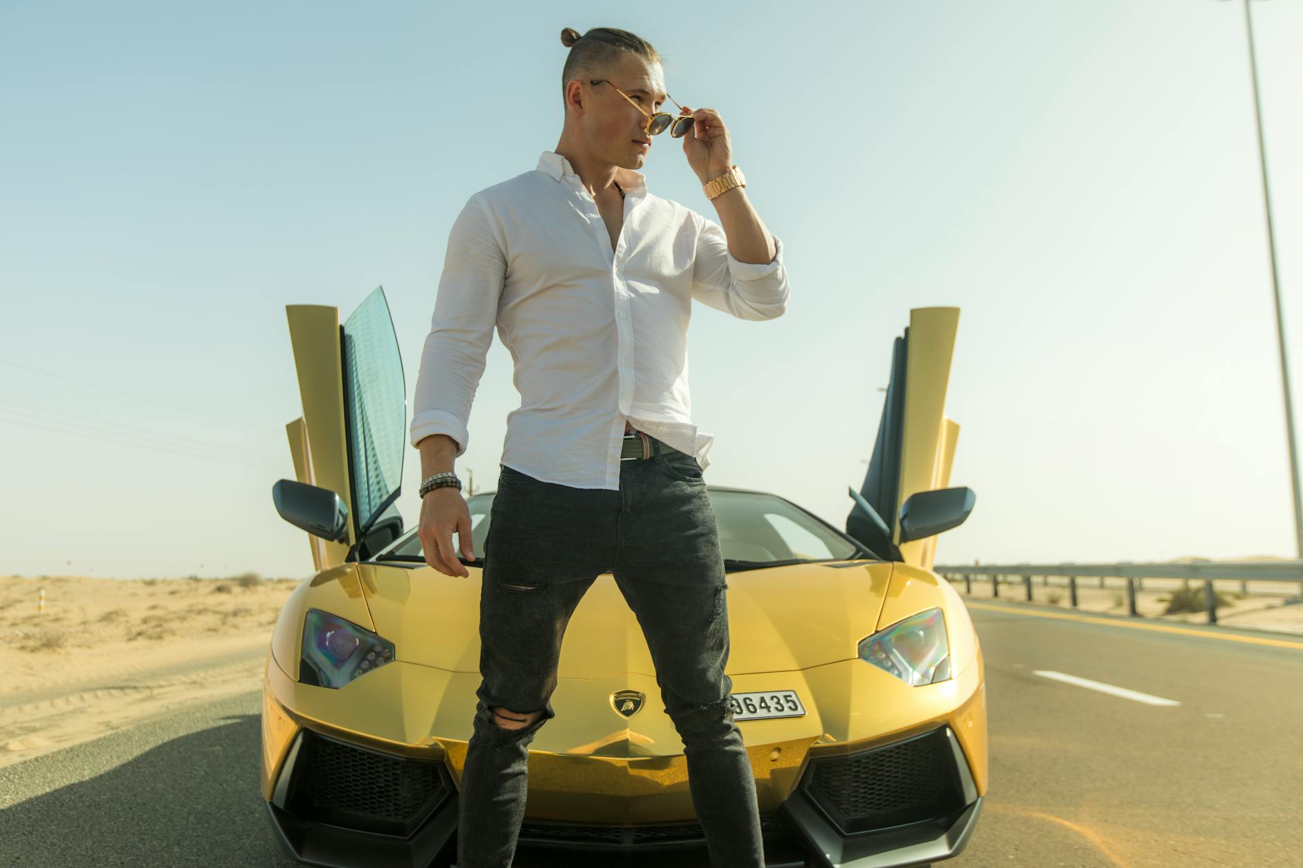 Mężczyzna przy żółtym Porsche poprawia okulary przeciwsłoneczne