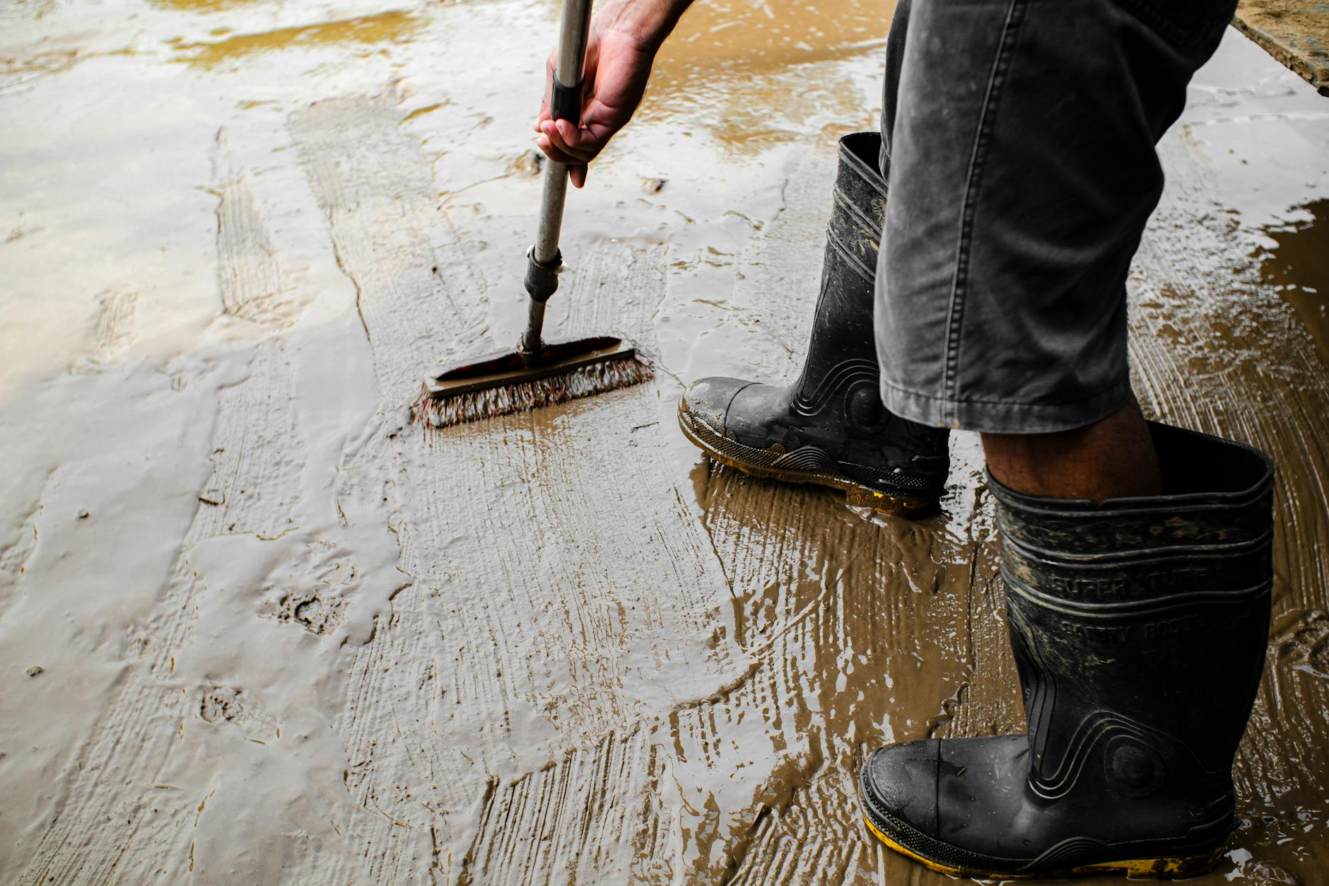 Pracownik w kaloszach nanosi preparat hydrofobowy na betonową posadzkę