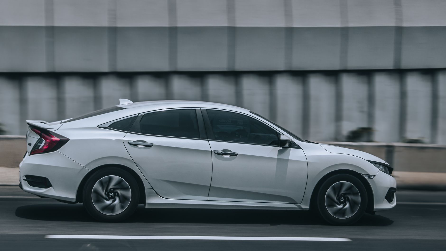 Biały Citroën C4 jedzie dynamicznie po miejskiej ulicy