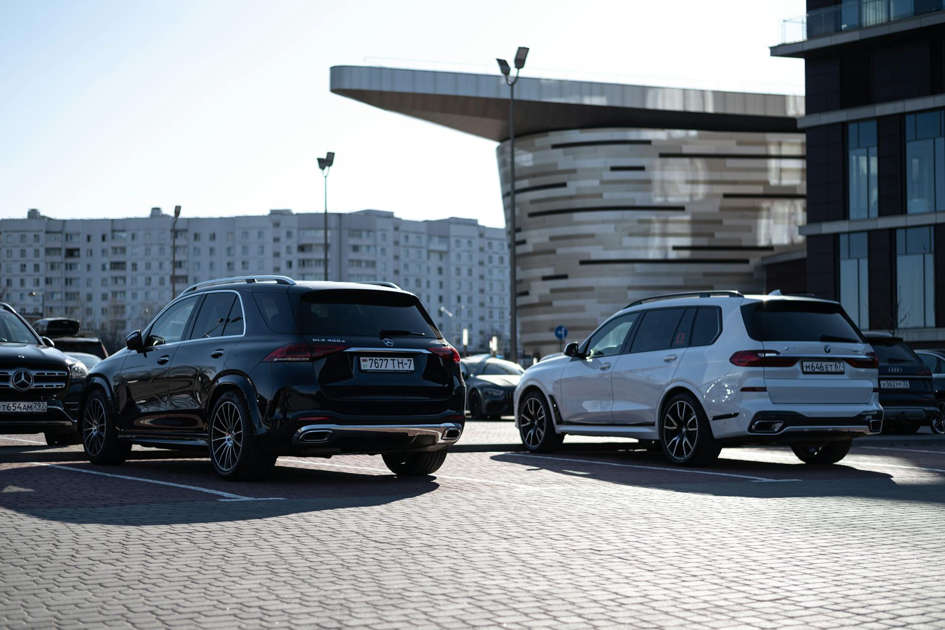 Dwa luksusowe SUV-y zaparkowane przy nowoczesnych budynkach w mieście