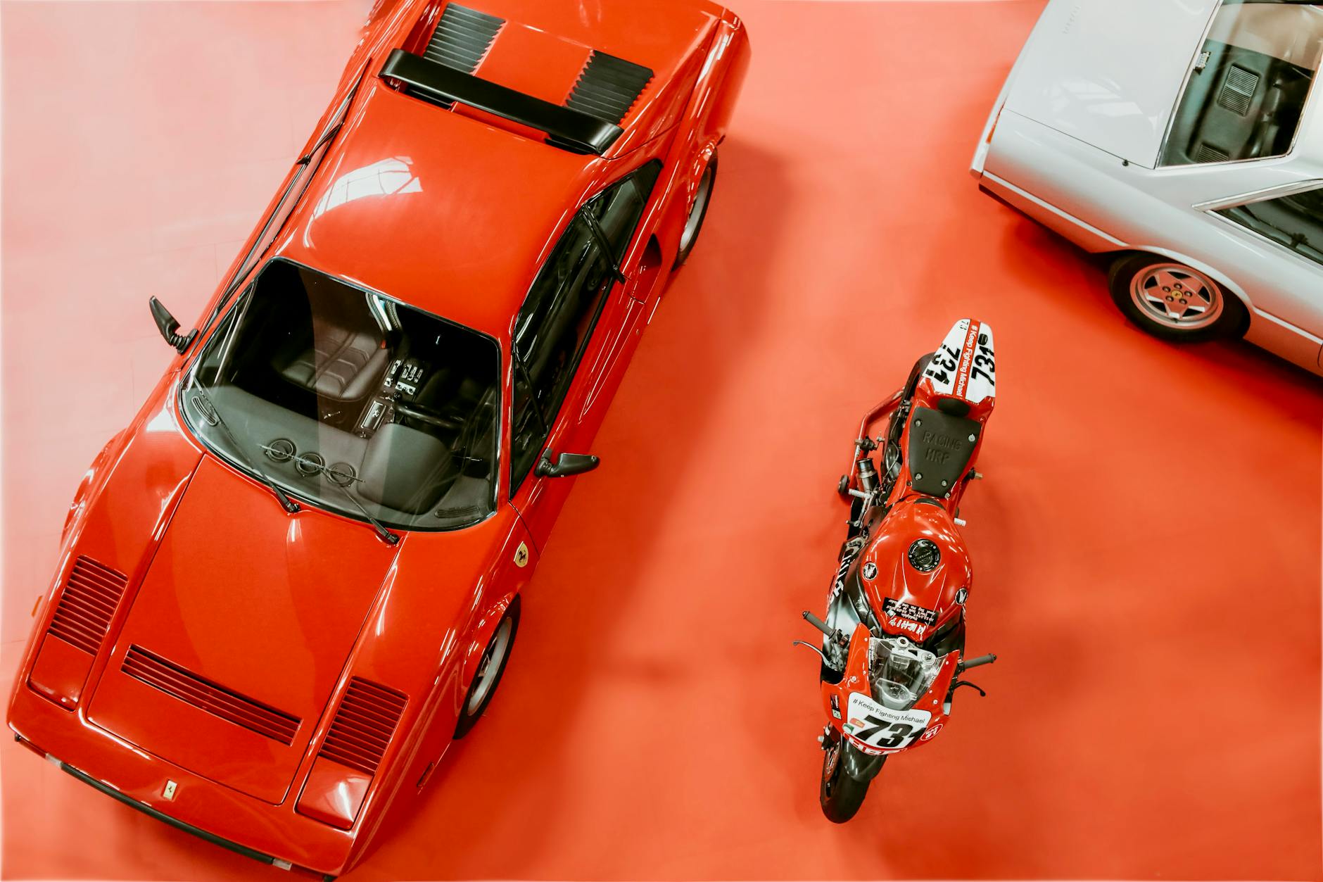 Klasyczne Ferrari i motocykl oglądane z góry na wystawie motoryzacyjnej