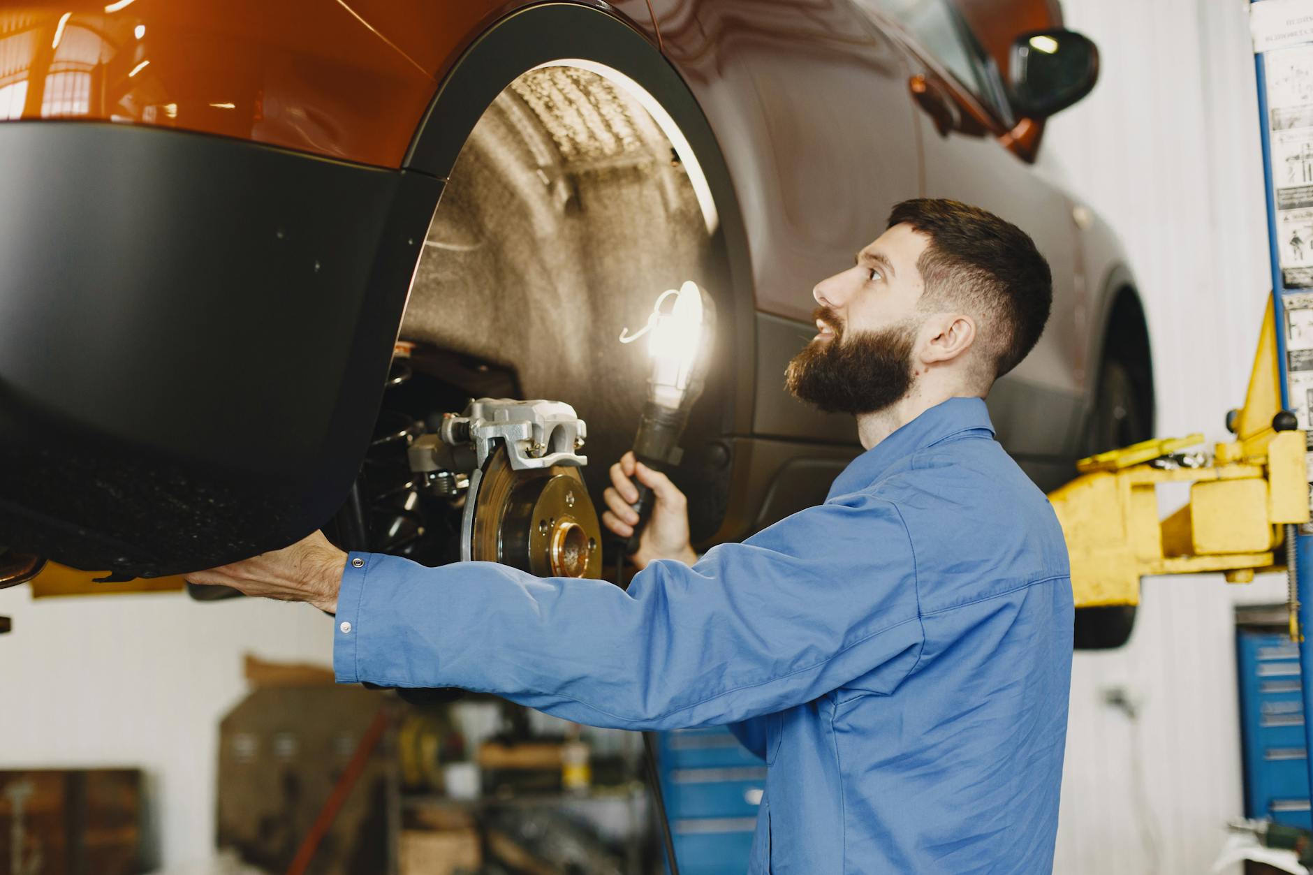 Mechanik w niebieskim kombinezonie sprawdza hamulce Cadillaca w warsztacie