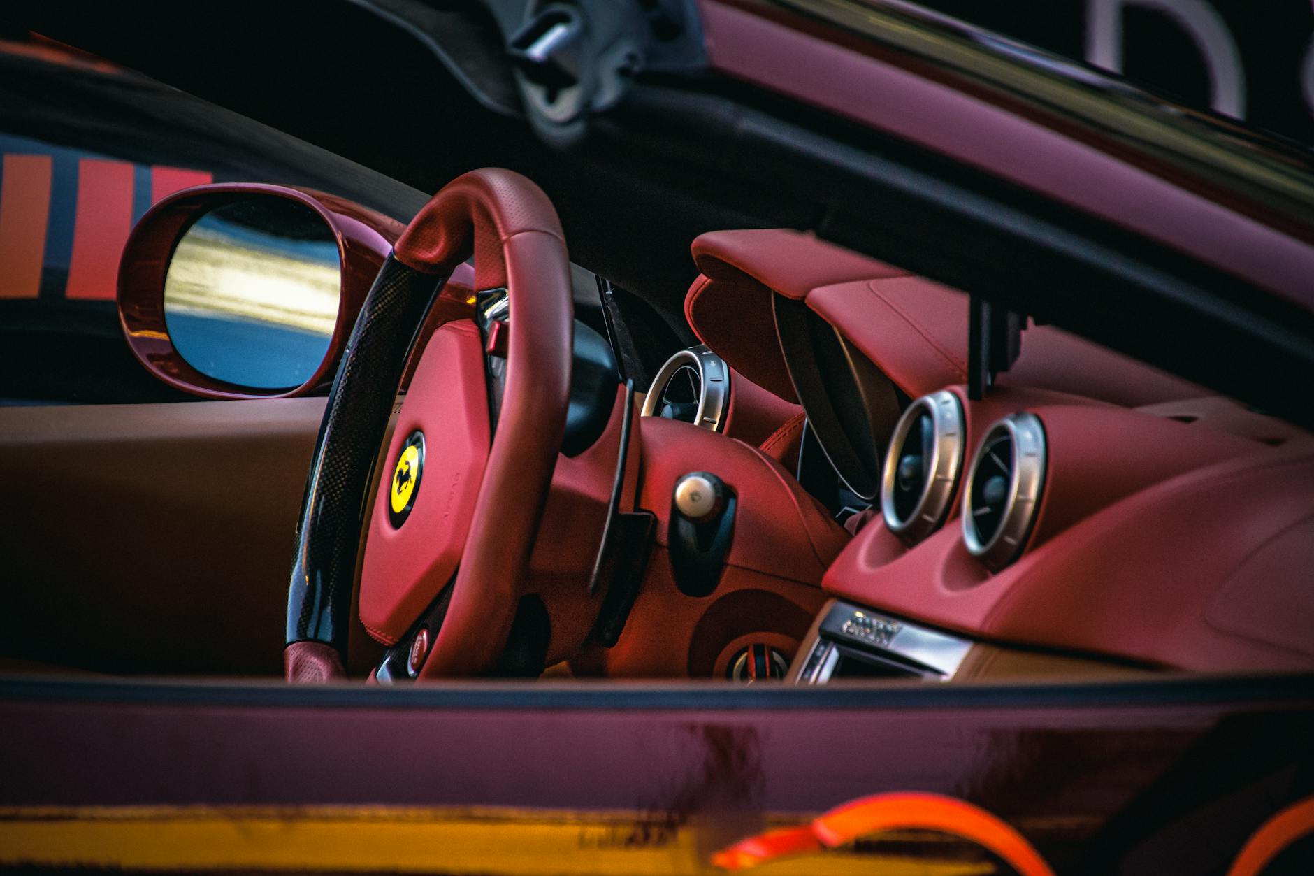 Wnętrze luksusowego Ferrari z czerwonymi skórzanymi fotelami i kierownicą