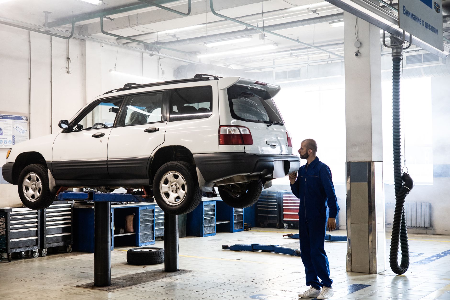 Mechanik sprawdza podniesionego SUV-a w nowoczesnym warsztacie